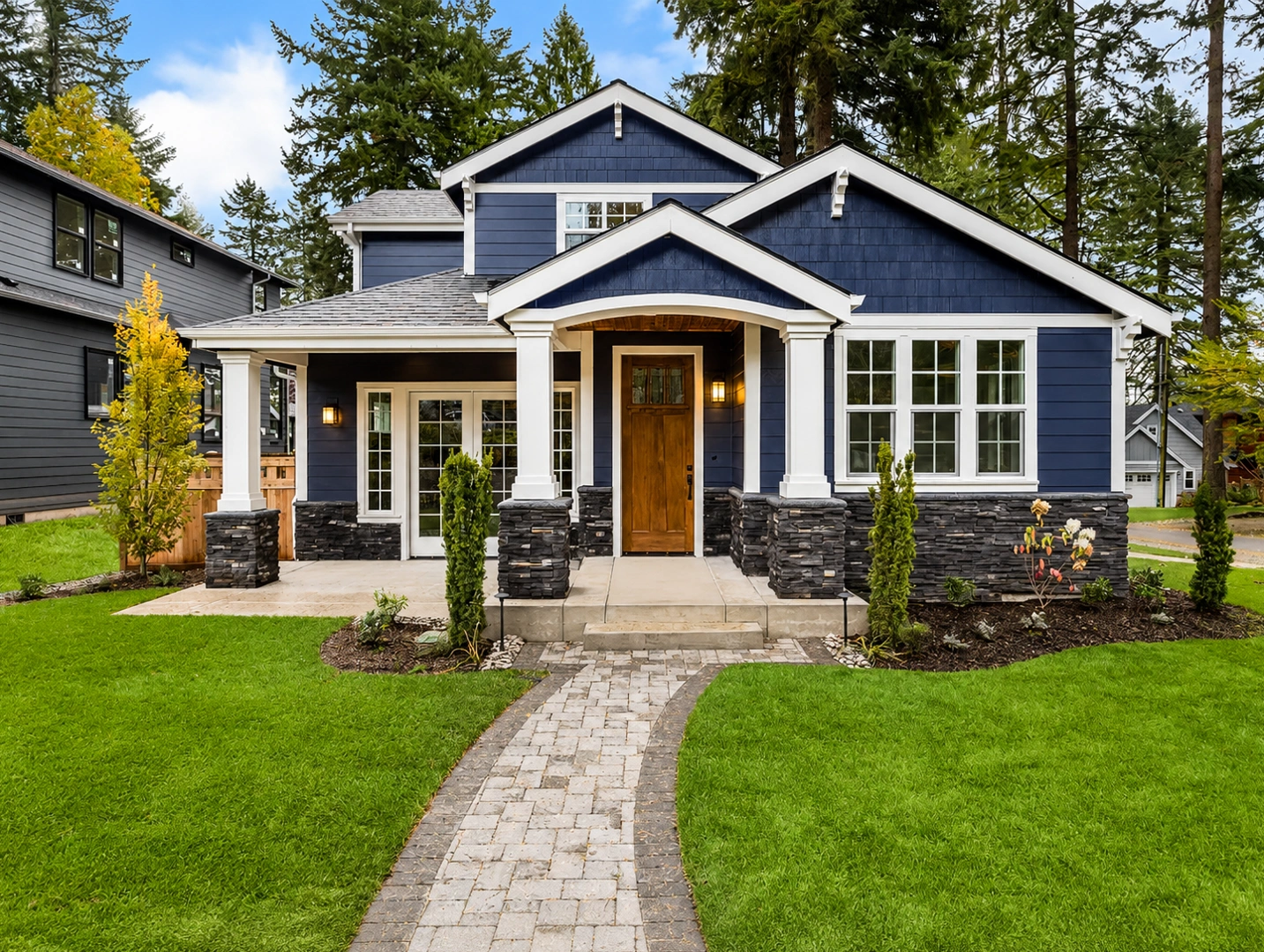 Navy blue craftsman home exterior with white trim and stone accents
