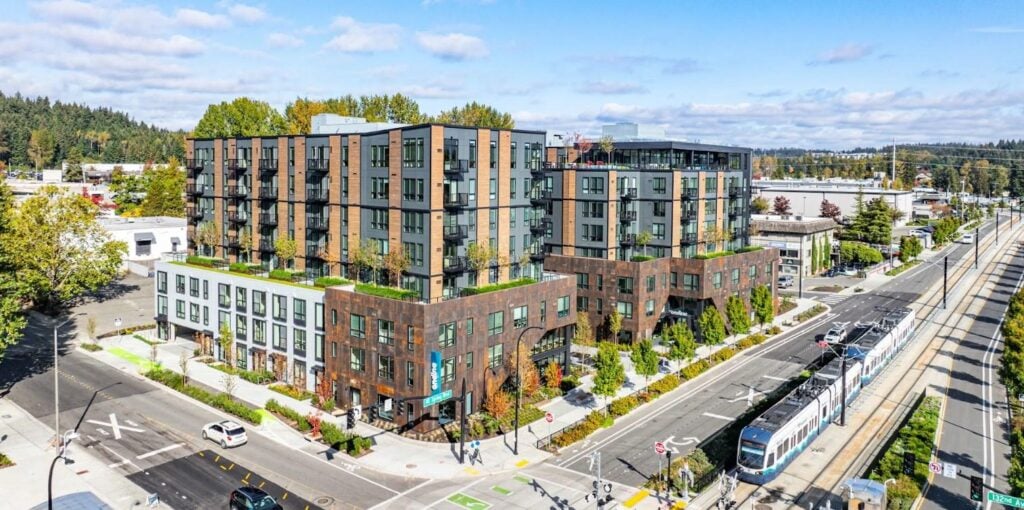 A multi-story residential complex under clear skies, proving summer is the best time to paint exterior of house.